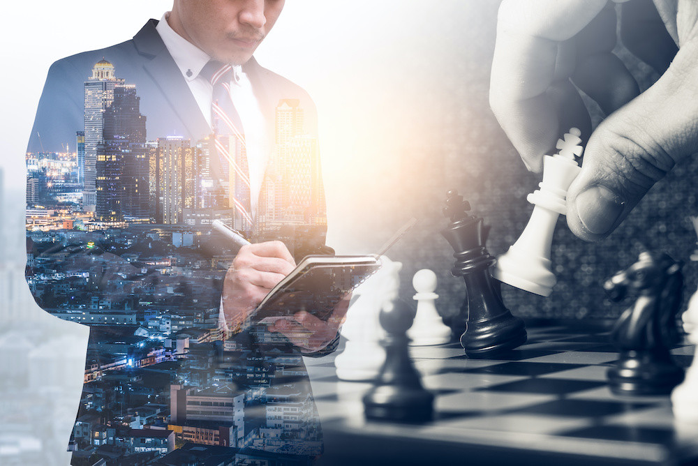 The double exposure image of the businessman writing on his notebook during sunrise overlay with chess game image.  the concept of strategy, victory, business, win, games, intelligence and education.